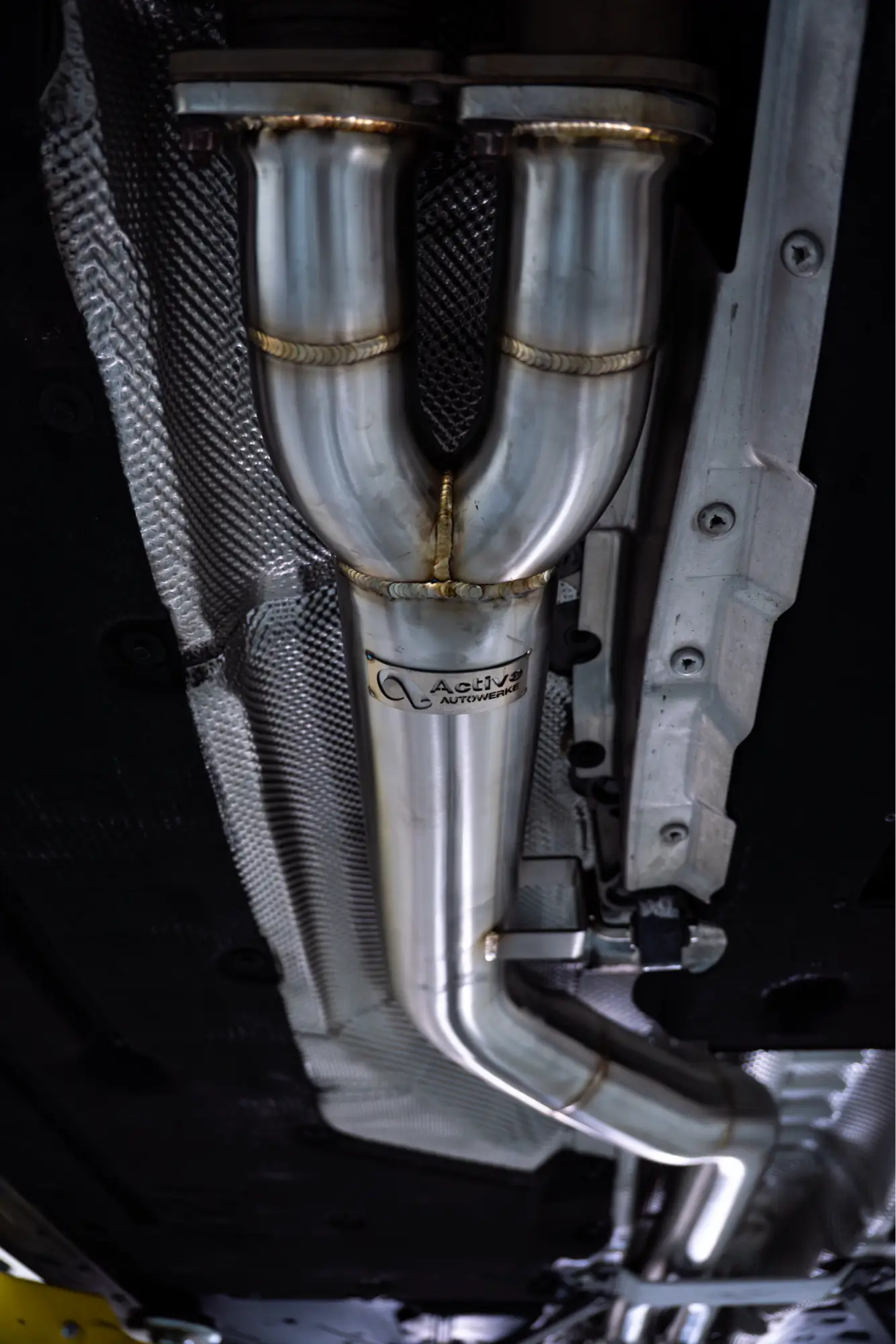 Close-up of an Active Autowerke exhaust downpipe during installation at HTP Motorsport.