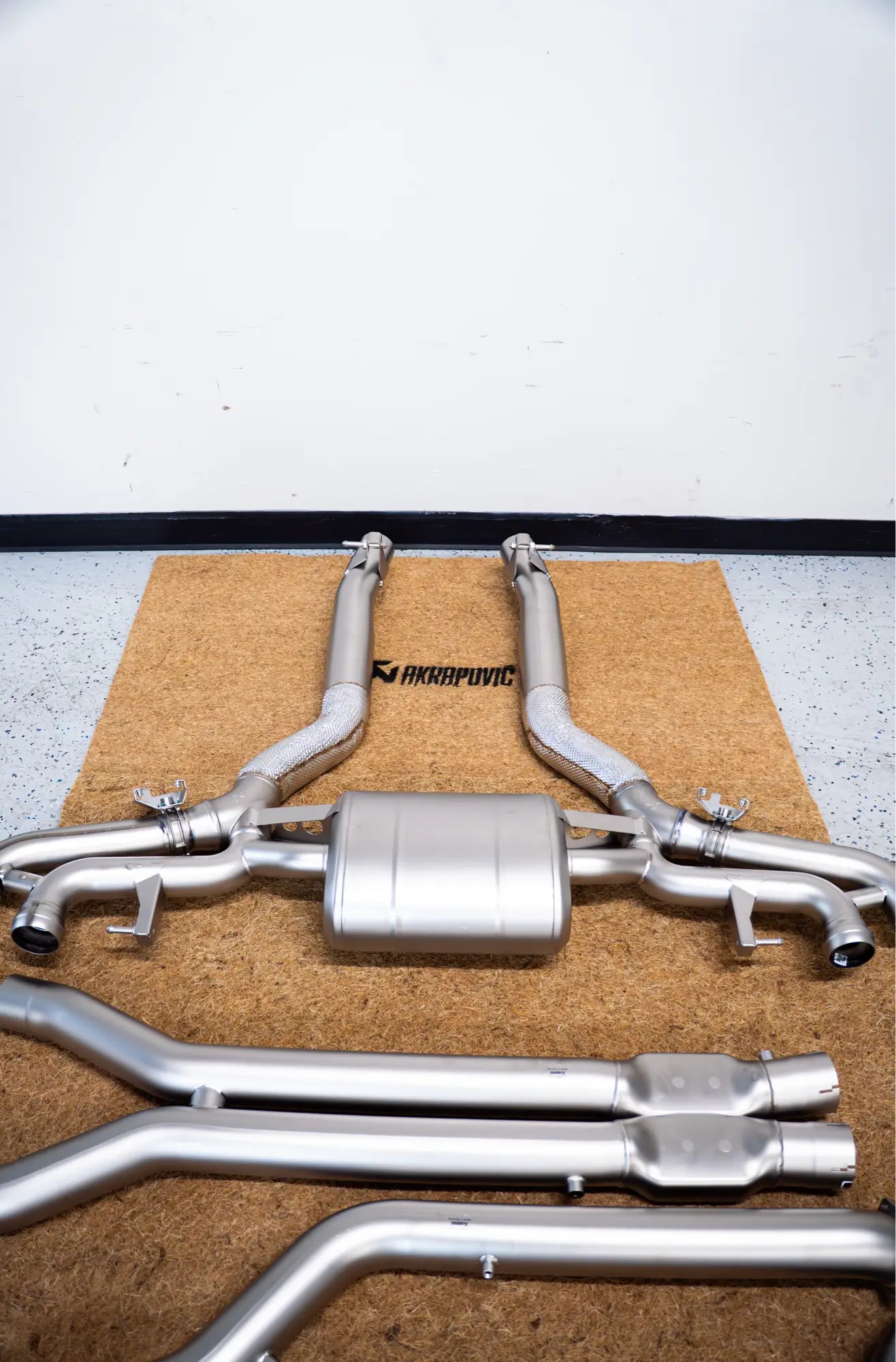 An Akrapovič exhaust system unboxed on the HTP Motorsport shop floor, ready for installation.
