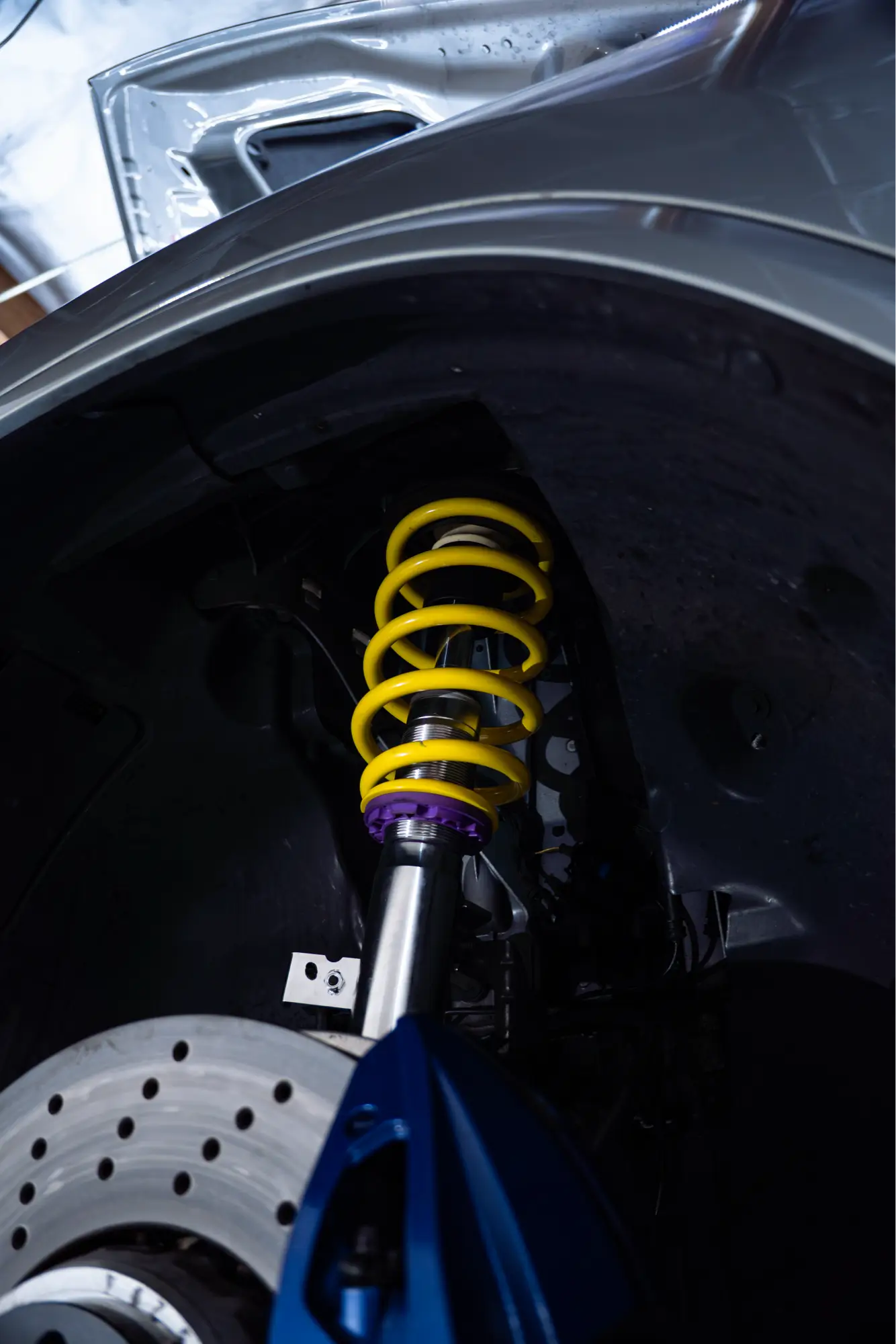 Close-up of a yellow coilover suspension spring beside a BMW's brake rotor.