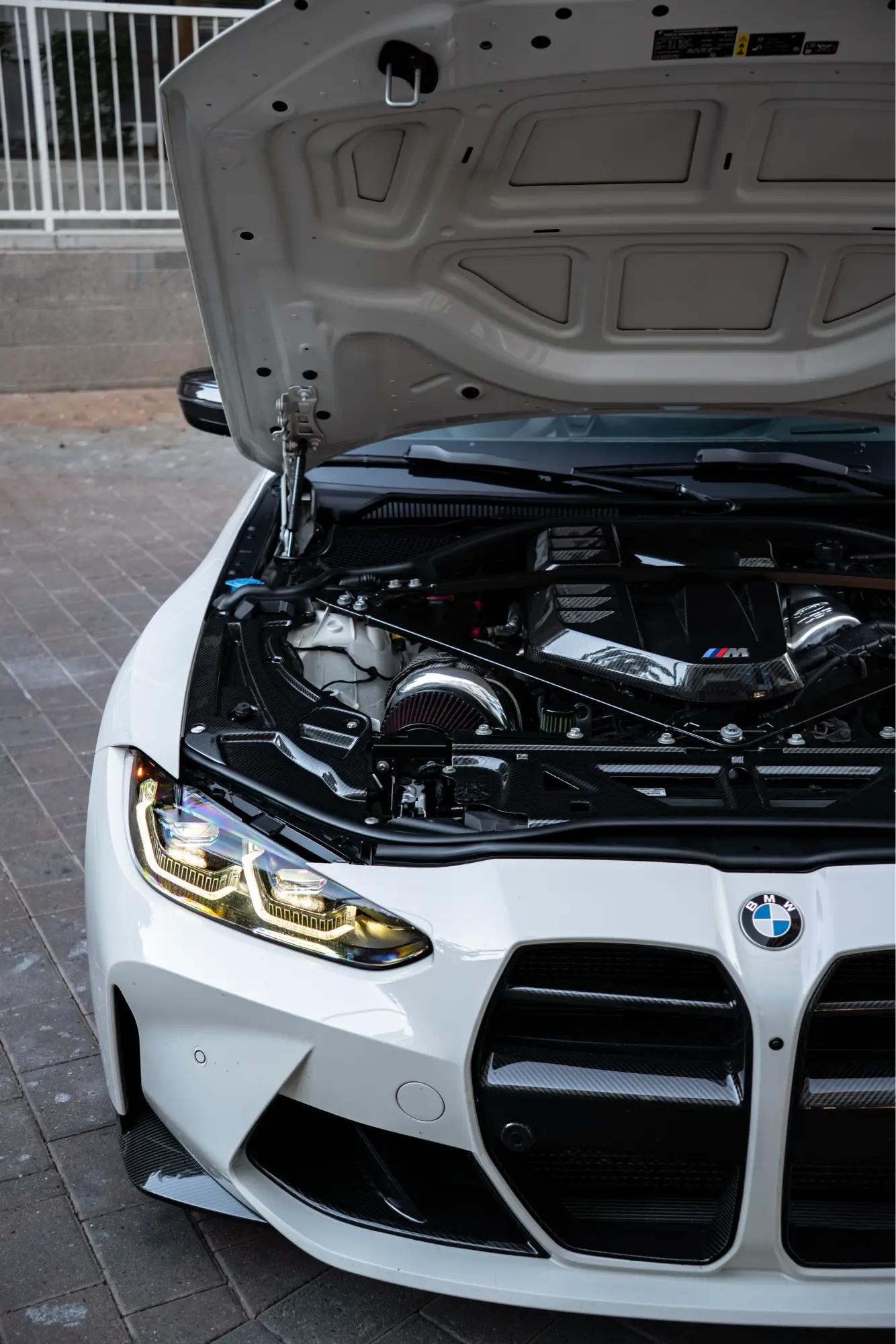 Close-up of a white BMW M4 (G82)'s engine bay.