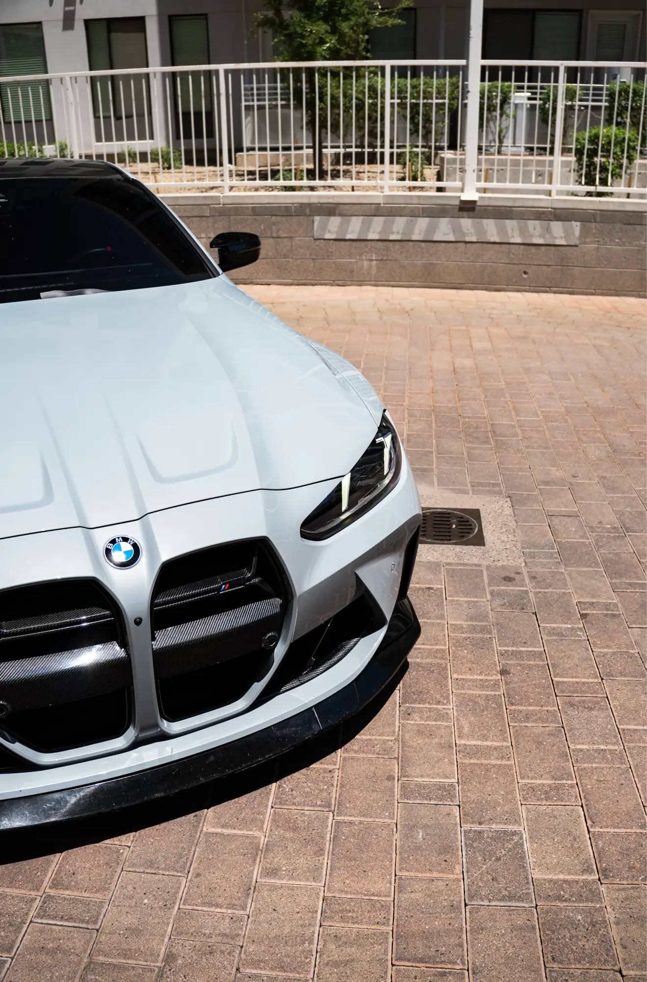 Close-up of a white BMW M4's front grille and badge outside a brick plaza, an example of cosmetic detail work at HTP Motorsport.