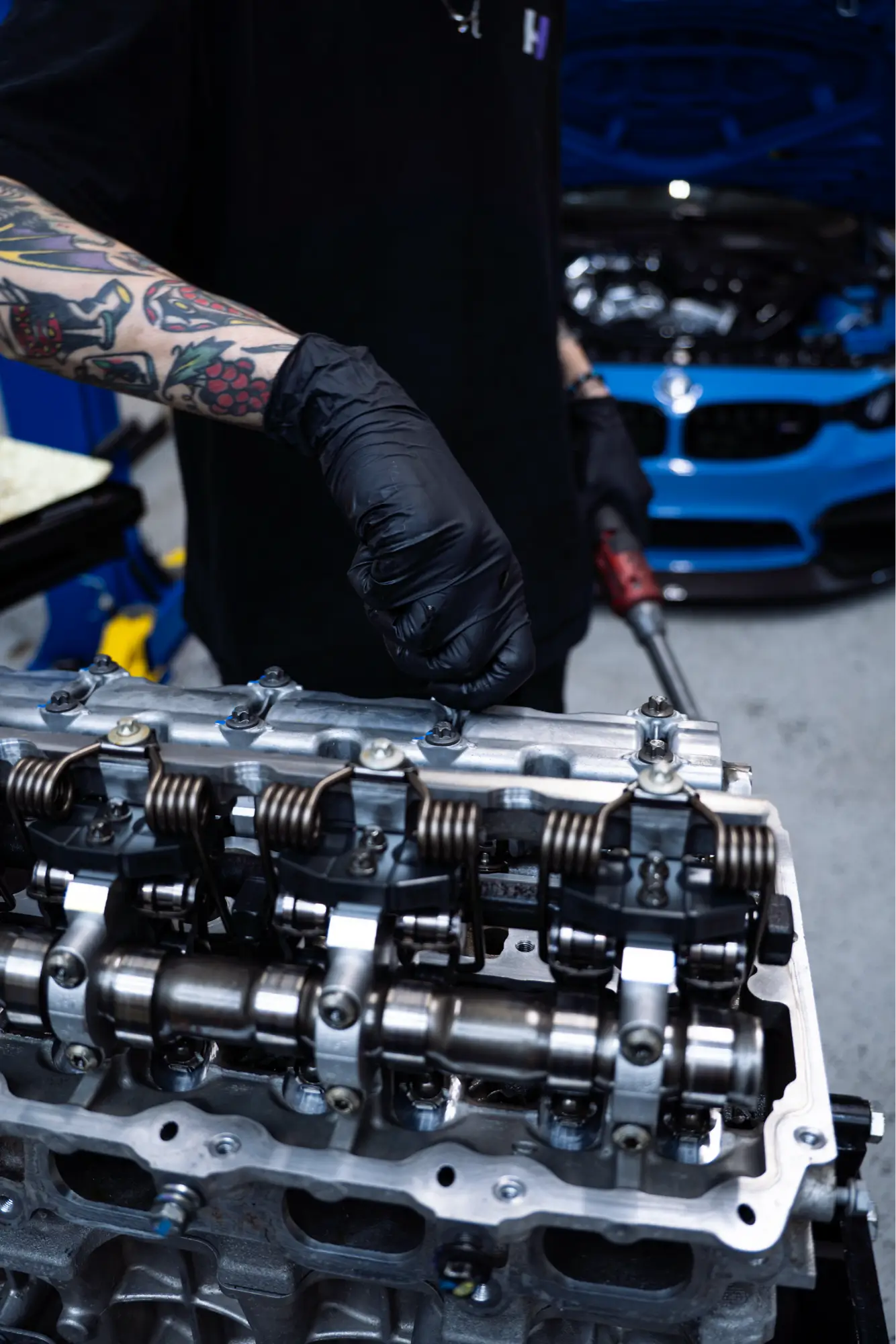 HTP Motorsport technician performing valve cover service on a vehicle's cylinder head.